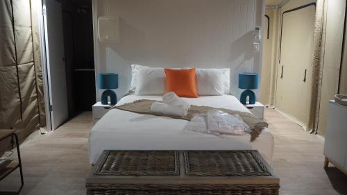 a bedroom with a large white bed with orange pillows at Magnetic Glamping in Nelly Bay
