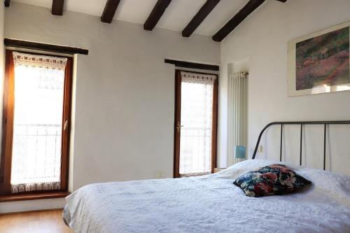 a bedroom with a bed and two windows at Casa di Borgo Santo Spirito in Parma
