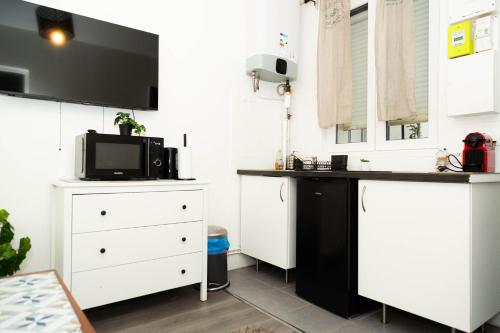 une cuisine avec des armoires blanches et un comptoir noir dans l'établissement Charment studio stade de France 18 pour 4 personnes, à Saint-Denis