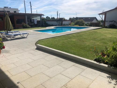 a backyard with a swimming pool and a lawn at Relaxando no campo in Viana do Castelo