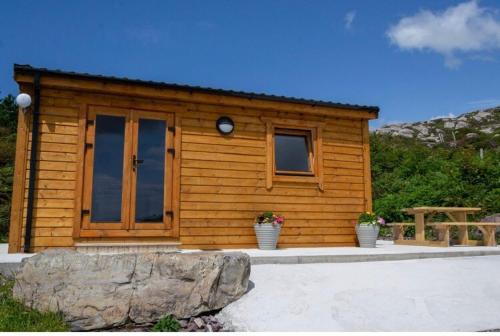 a small wooden cabin with a rock in front of it at Dolphin View Lambs Head in Caherdaniel