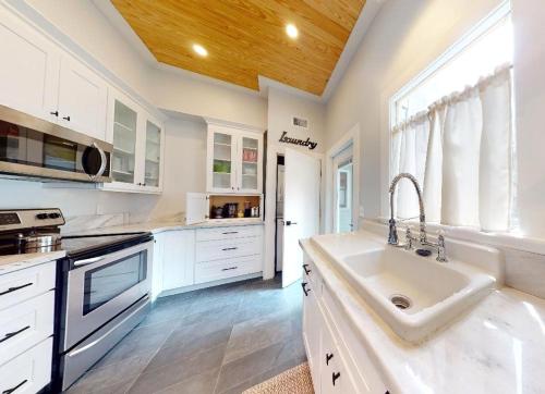 a white kitchen with a sink and a window at Palm Paradise - Renovated 1891 Queen Anne - Historic DT Quarter Mi Stroll - Beach only 3 Mi in Saint Augustine
