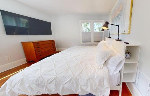 a bedroom with a white bed and a tv at Palm Paradise - Renovated 1891 Queen Anne - Historic DT Quarter Mi Stroll - Beach only 3 Mi in Saint Augustine