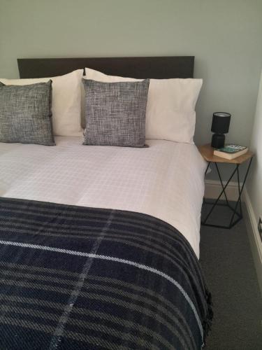 a bedroom with a large bed with pillows and a table at Doune 3 Outlander Apartment 1st floor in Stirling