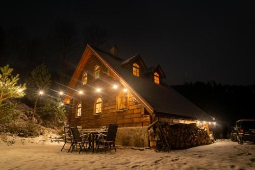 a wooden cabin with a table and chairs in the snow at Forest Camp Dom w Górach Sowich in Michałkowa