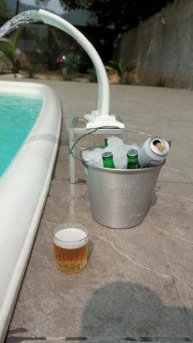 a bucket with bottles in it next to a swimming pool at Recanto da Cachoeira RJ in Magé