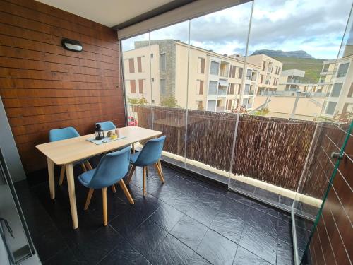 Una mesa y sillas en un balcón con ventana. en Las Margas Apartamento, en Sabiñánigo