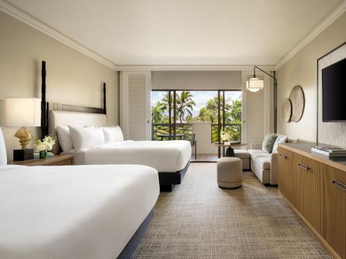 a hotel room with two beds and a television at Fairmont Orchid in Waikoloa