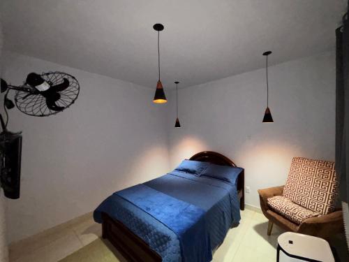 a bedroom with a bed and a chair and lights at Recanto da Cachoeira RJ in Magé