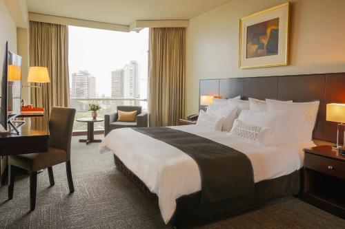 a hotel room with a large bed and a desk at Delfines Hotel & Convention Center in Lima