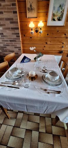 a table with a white table cloth and plates on it at Chalet with Stunning Lake and Mountain Views avec une vue à couper le souffle, une spacieuse terrasse et jardin in Châtillon