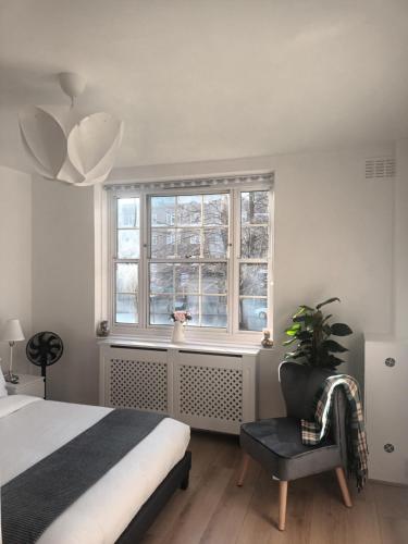 a bedroom with a bed and a chair and a window at Good Charming Apartment in London