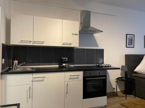 a kitchen with white cabinets and black counter tops at City Apartments Trier Suite 5 in Trier