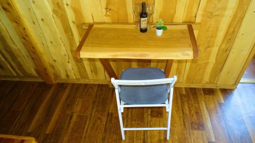 a wooden table with a chair and a bottle of beer at Refugio del Chucao in Llanada Grande