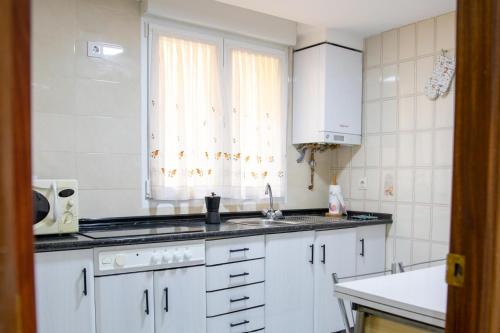 une cuisine avec des armoires blanches, un évier et une fenêtre dans l'établissement MAGIC II a 30 segundos de la Plaza Mayor y 1 minuto de la Catedral, à León