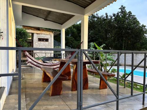 a patio with a hammock and a table on a balcony at Recanto da Cachoeira RJ in Magé