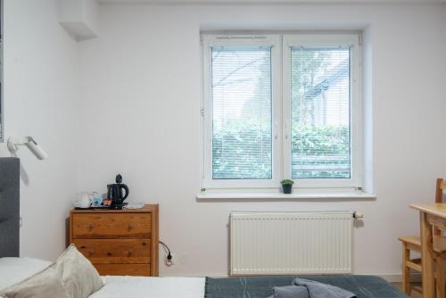 a bedroom with two windows and a wooden dresser at Studio I Pokoje I Pokoje z łazienkami in Gdańsk