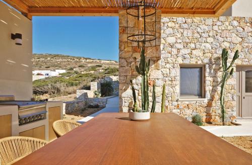 a kitchen with a wooden table in front of a stone building at Agave Donousa Suites in Donoussa