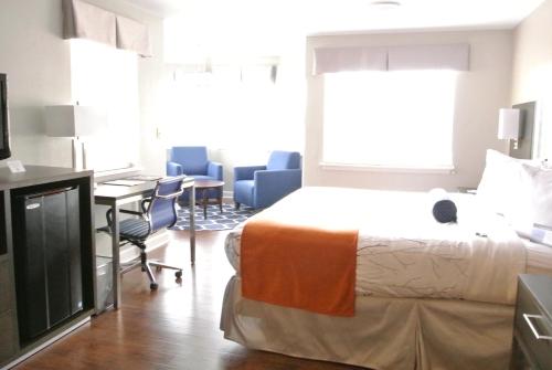 a hotel room with a bed and a desk and chairs at Guesthouse Inn & Suites Lexington in Lexington