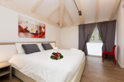 a bedroom with a white bed with a flower arrangement on it at Residence Klima House de Vilos in Arco