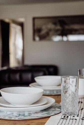 a table with plates and bowls and a glass of water at Lake Mahinapua Hotel in Ruatapu