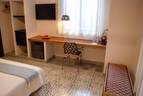 a bedroom with a desk and a bed and a window at Hotel Casa de la Acequia in Santa Marta