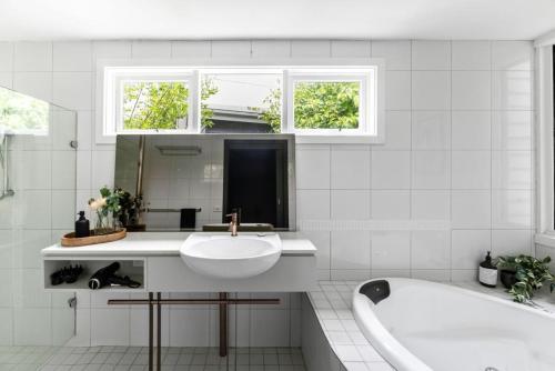 a white bathroom with a tub and a sink and a bath tubermott at Romantic Lakefront Luxury - Spa Bath, Fireplace, King Bed in Daylesford