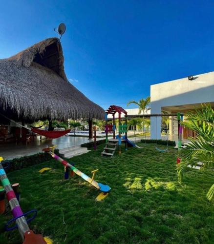a playground in a resort with a straw umbrella at Villa Maty Casa Campestre in Turbaco