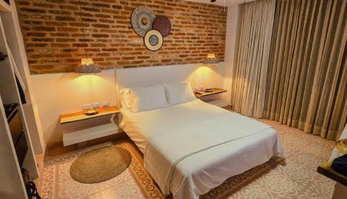 a bedroom with a bed and a brick wall at Hotel Casa de la Acequia in Santa Marta