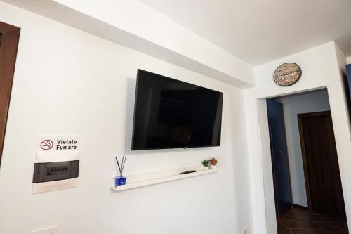 a flat screen tv on a white wall with a clock at Materò House - Nel cuore di Alfedena in Alfedena