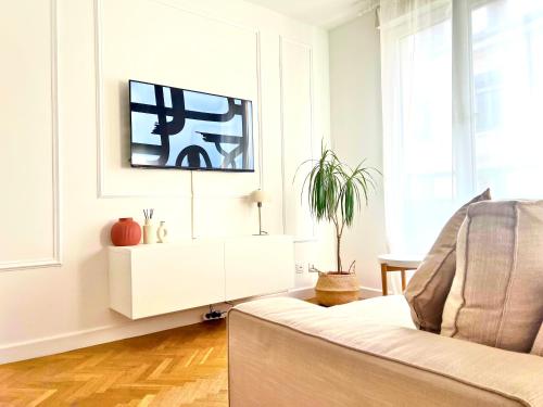 un salon avec un canapé et une télévision sur un mur dans l'établissement Lyon Suite Cosy - Climatisé - Appartement T2 - Proche Parc Tête d'Or, à Villeurbanne