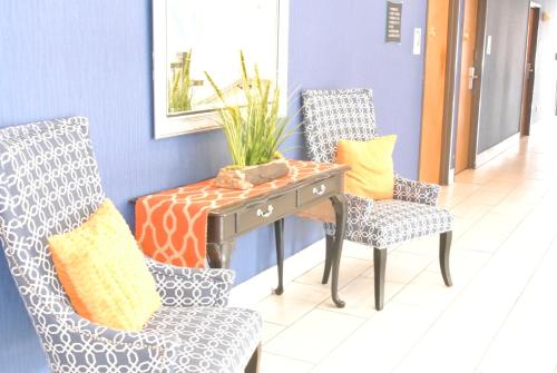 a desk with two chairs and a table with a plant on it at Guesthouse Inn & Suites Lexington in Lexington