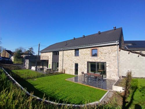 a brick house with a patio and a yard at Gite chez Martin in Jalhay