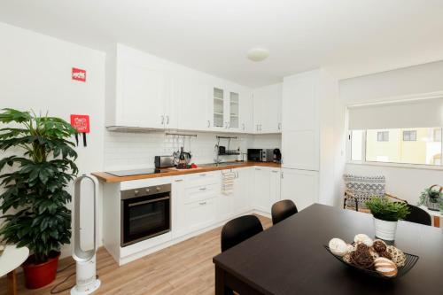 a kitchen with white cabinets and a table with a bowl of food at NayJay Staycation in Portimão
