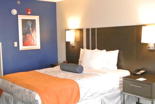 a hotel room with a bed with an orange blanket on it at Guesthouse Inn & Suites Lexington in Lexington
