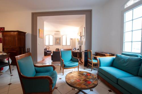 un salon avec un canapé bleu et des chaises dans l'établissement La Bastide - Clim, jardin, Parking, à Arles