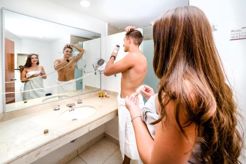 a woman standing in a bathroom looking at a man in a mirror at Uxmal Resort Maya in Uxmal