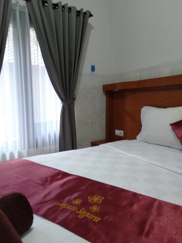 a bedroom with a large bed and a window at Jepun Segara Guest House in Kuta