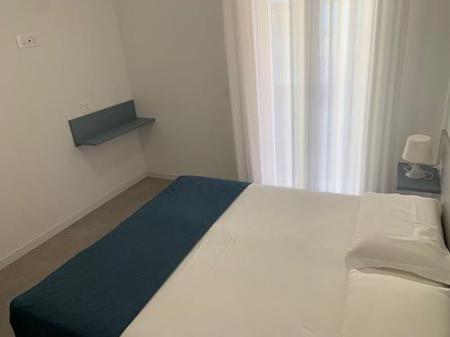 a bedroom with a white bed with a blue blanket at Matilde Apartments Caorle in Caorle