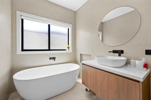 a white bathroom with a sink and a mirror at Stunning Beach Side Family Home in St Leonards in Saint Leonards