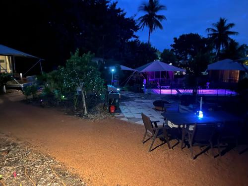 a patio with a table and chairs at night at Magnetic Glamping in Nelly Bay