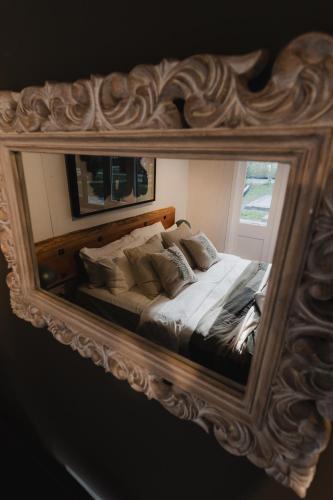 a mirror reflecting a bed in a bedroom at Lake Mahinapua Hotel in Ruatapu