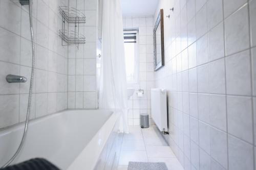 a white bathroom with a tub and a shower at Oberwiesenthal Apartments in Kurort Oberwiesenthal