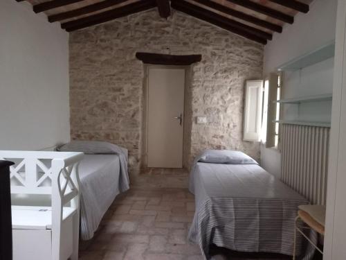 Un dormitorio con dos camas y una pared de piedra. en Casa intera con giardino, en Mantignana