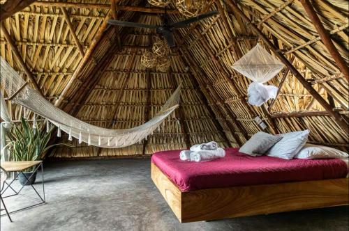a bedroom with a hammock in a thatched room at BarriOceano in El Paredón Buena Vista