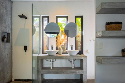 a bathroom with two sinks and two mirrors at BarriOceano in El Paredón Buena Vista