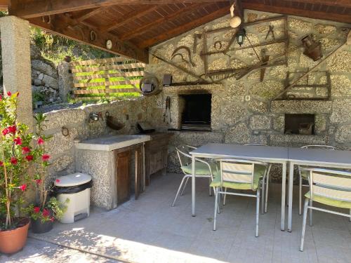 a patio with a table and chairs and a stone wall at Leiras da Cachada - Gerês in Valdosende