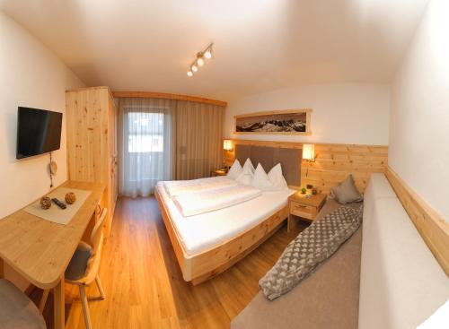 a bedroom with a bed and a desk and a table at Hotel Garni Savoy - new opening in Castelrotto