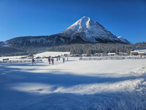 a mountain in the background with people walking in the snow at Alpenlandhaus Menardi in Seefeld in Tirol