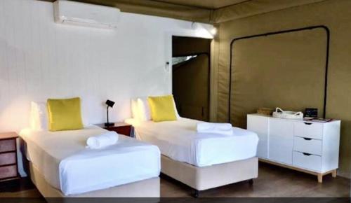two beds with yellow pillows in a room at Magnetic Glamping in Nelly Bay